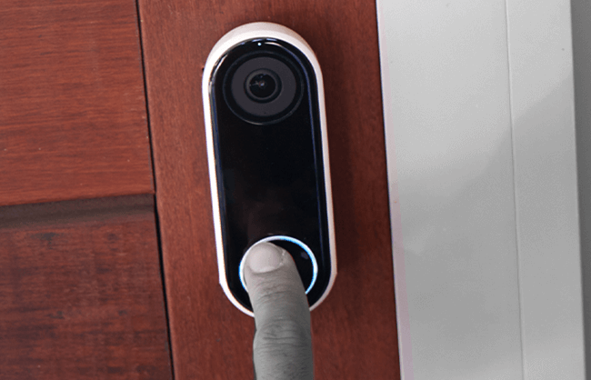 Close-up of someone pushing on a smart doorbell