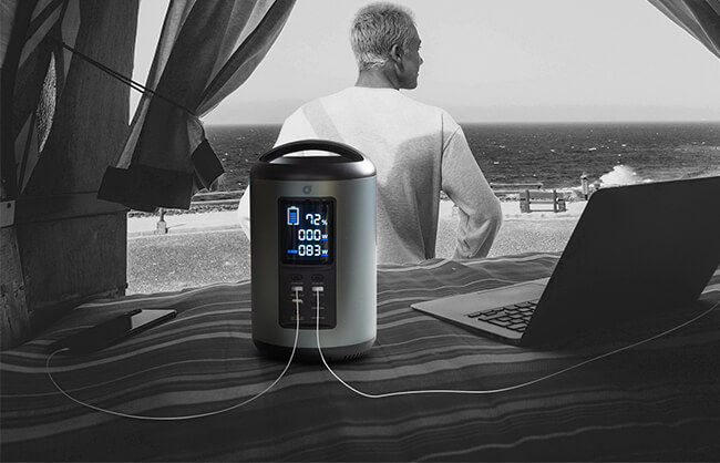 Lifestyle image of aviva portable power station in van plugged into a laptop while a man looks out to the beach