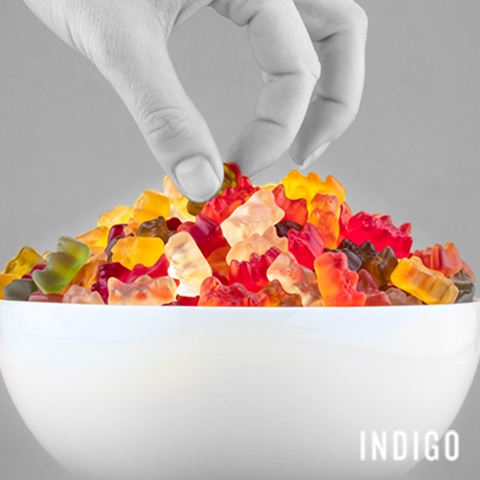 Closeup of woman's hand picking up gummy bears out of a bowl