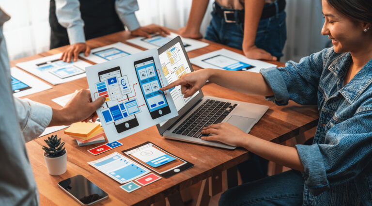 Panorama shot of front-end developer team brainstorming UI and UX designs for mobile app on paper wireframe interface. UX design team planning for user-friendly UI design.