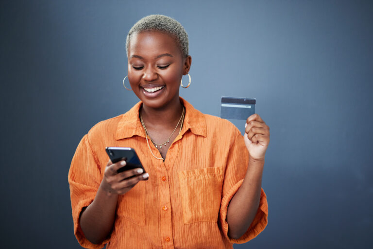 Smile, phone and credit card with a black woman online shopping in studio on a gray background. Mobile, ecommerce and finance payment with a happy young female shopper searching for a deal or sale.