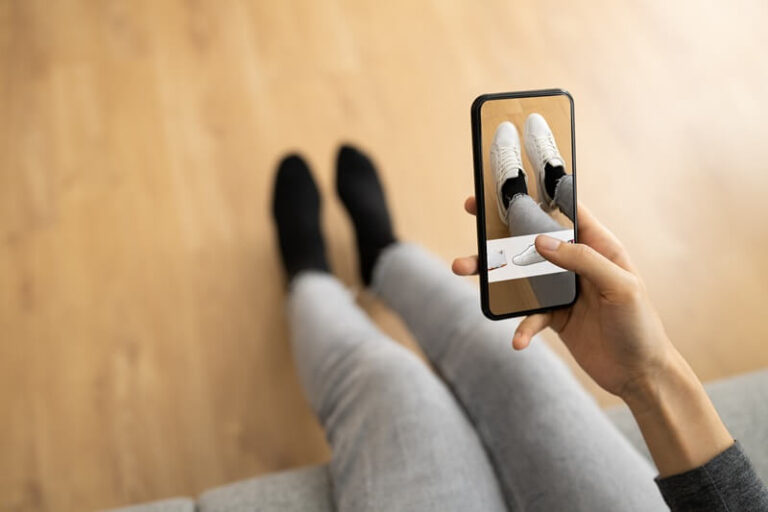 A person looking at a pair of shoes on a cellphone.